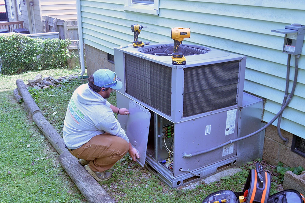 Cumberland Cooling employee with tools taking panel off of AC unit to do maintenance