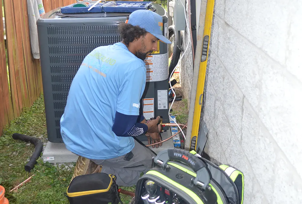 Employee installing a new HVAC unit on the side of a house