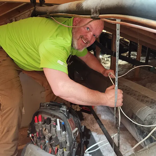 Cumberland Cooling owner John Mark with tool bag connecting wires in an attick next to ductwork