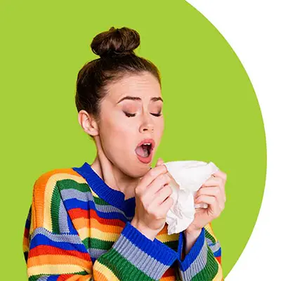 Woman sneezing into tissue