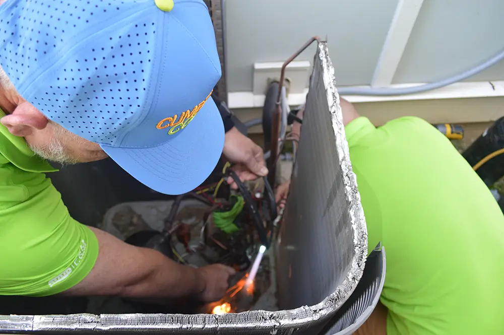 Two technicians repairing a heat pump
