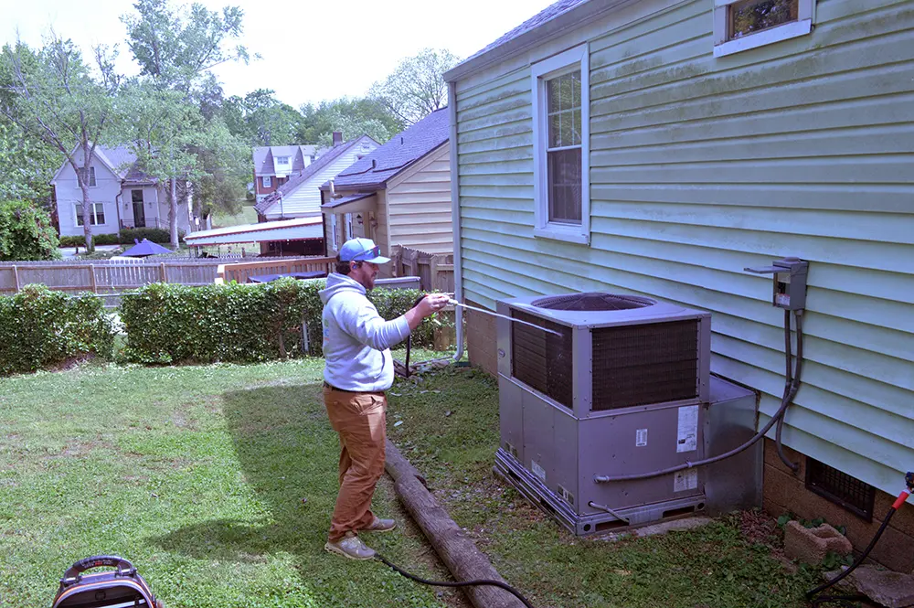 Spraying off HVAC unit as part of maintenance