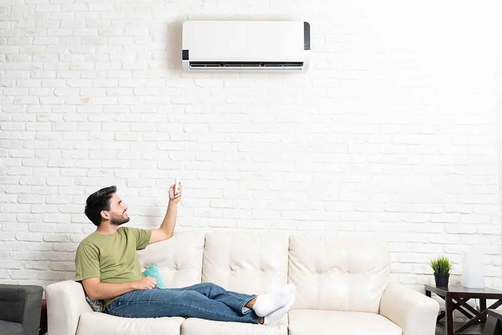 Man sitting on couch with remote control to mini-split system