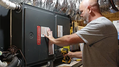 Owner of Cumberland Cooling opening HVAC with a drill to repair and service it