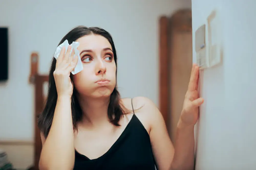 Frustrated woman looking at thermostat